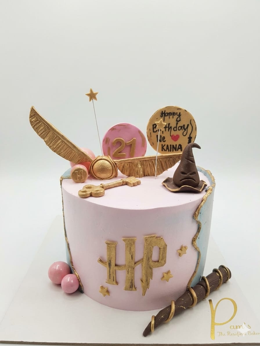Eggless Harry Potter theme birthday cake with pink fondant finish, gold Harry Potter's  logo, golden Snitch, Sorting Hat, magic wand and personalised name topper custom fantasy theme cake available to order online at Pam's Bakery, Sector 75, Spectrum Metro Mall, Noida