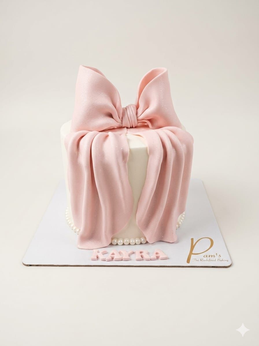Cylindrical cake with a large pink bow on top, set against a light background.