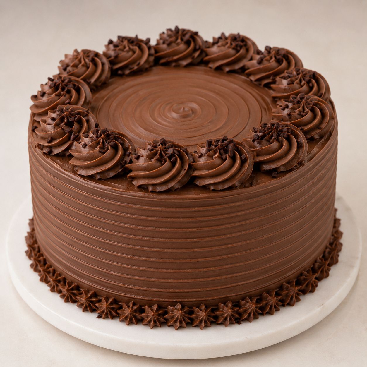 Eggless classic chocolate cake with smooth ridged buttercream finish, piped chocolate rosettes, chocolate chip sprinkles and star border.Freshly baked and available to order online at Pam's Bakery, Sector 75, Spectrum Metro Mall, Noida
