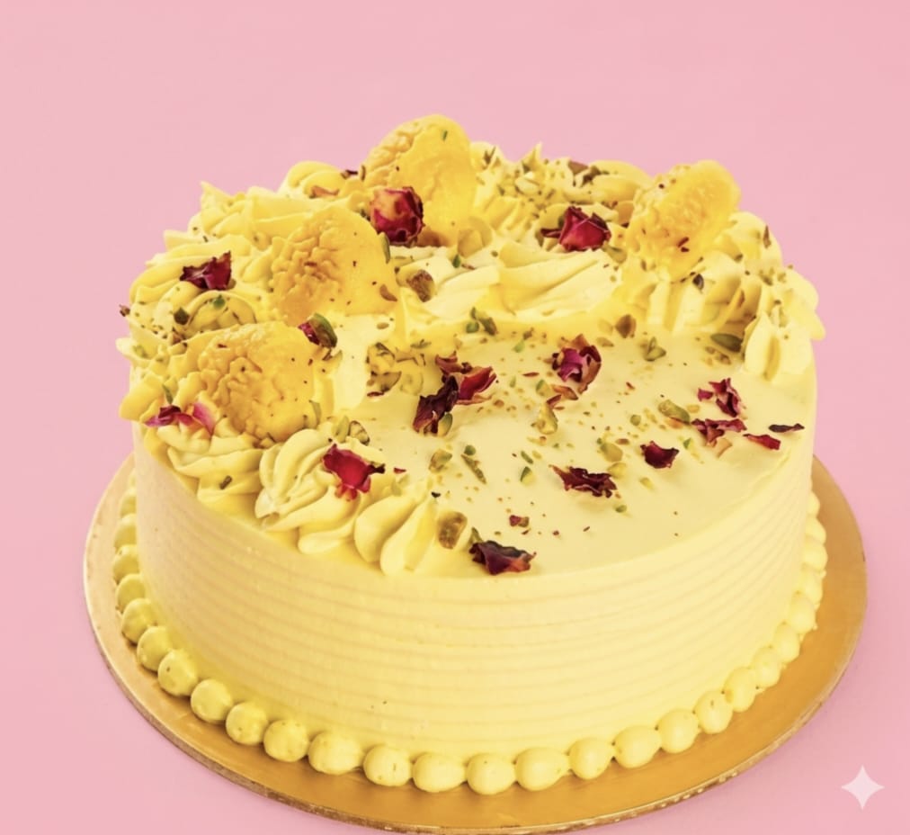 Eggless mango rabri cake with pale yellow ridged cream finish, piped mango rosettes, dried rose petals, crushed pistachios and cardamom , traditional Indian flavour fusion cake freshly baked and available to order online at Pam's Bakery, Sector 75, Spectrum Metro Mall, Noida